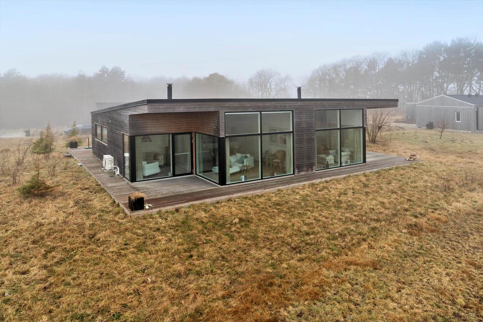 Moderne Villa mit großem Holzterrasse und Glasfronten im Freien.