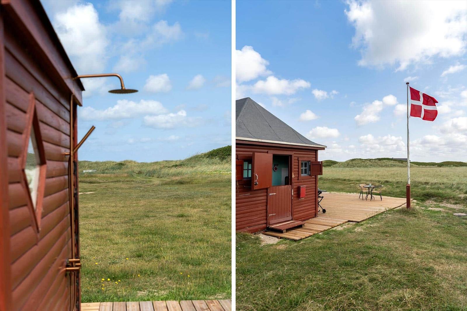 Hütte mit Dusche im Freien und Terrasse mit Flagge.