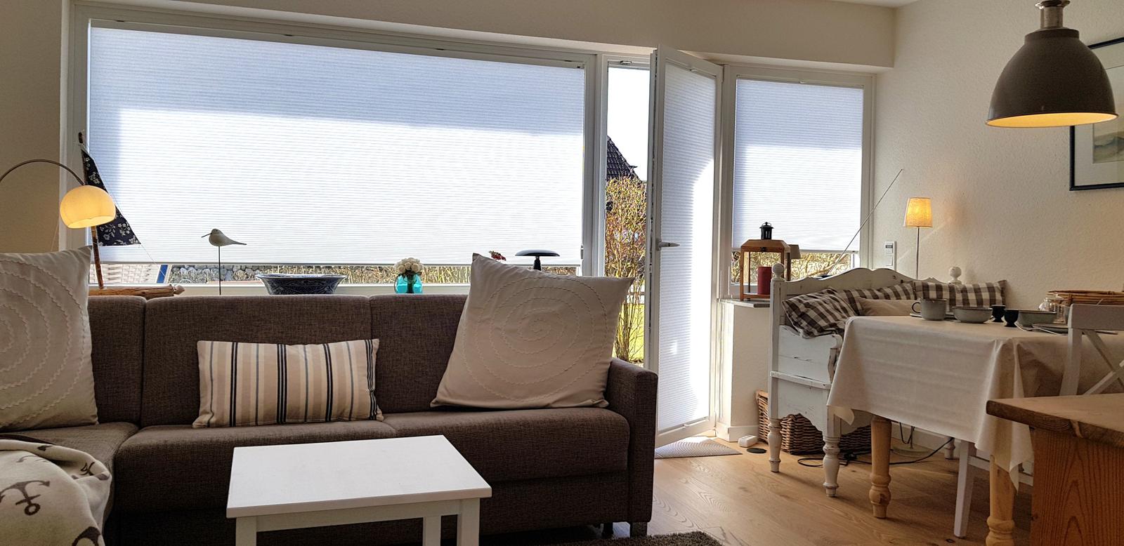 Wohnzimmer mit Sofa, Tisch und Fenster zur Terrasse.