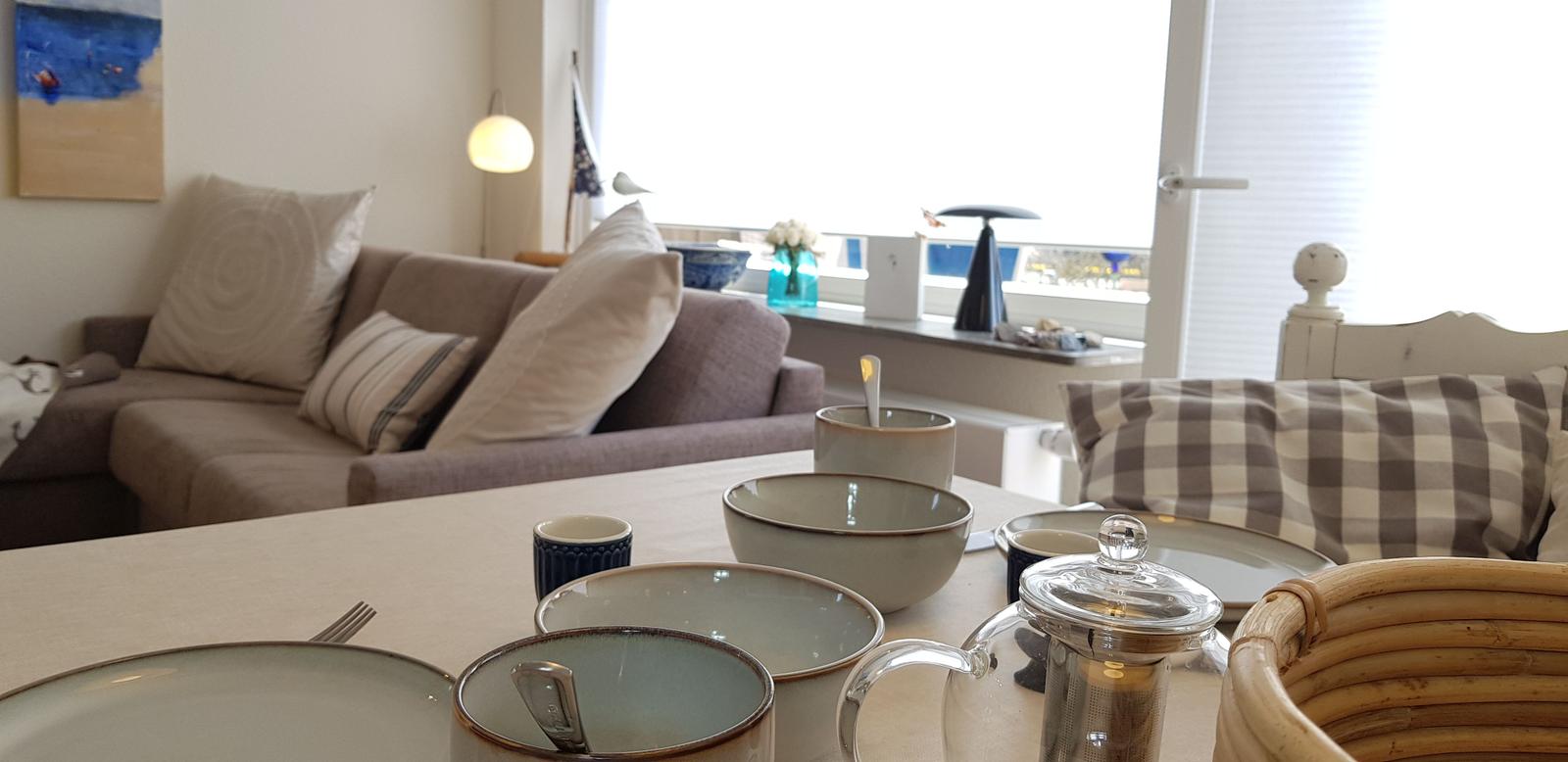 Esstisch mit Tassen und Tassen, Sofa und Fensterblick.