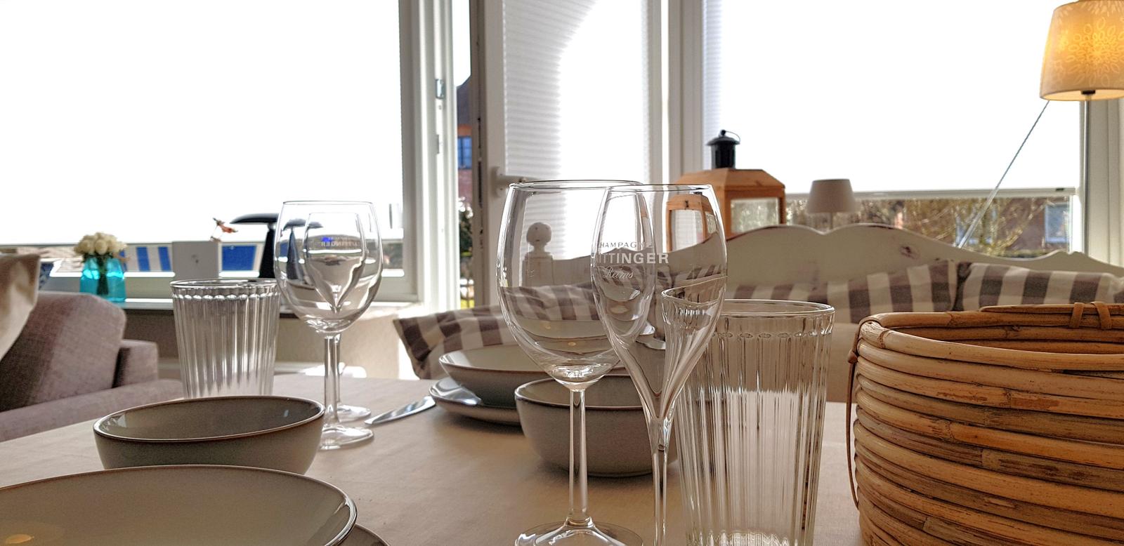 Tisch mit Gläsern, Tellern und Korb vor Fenster