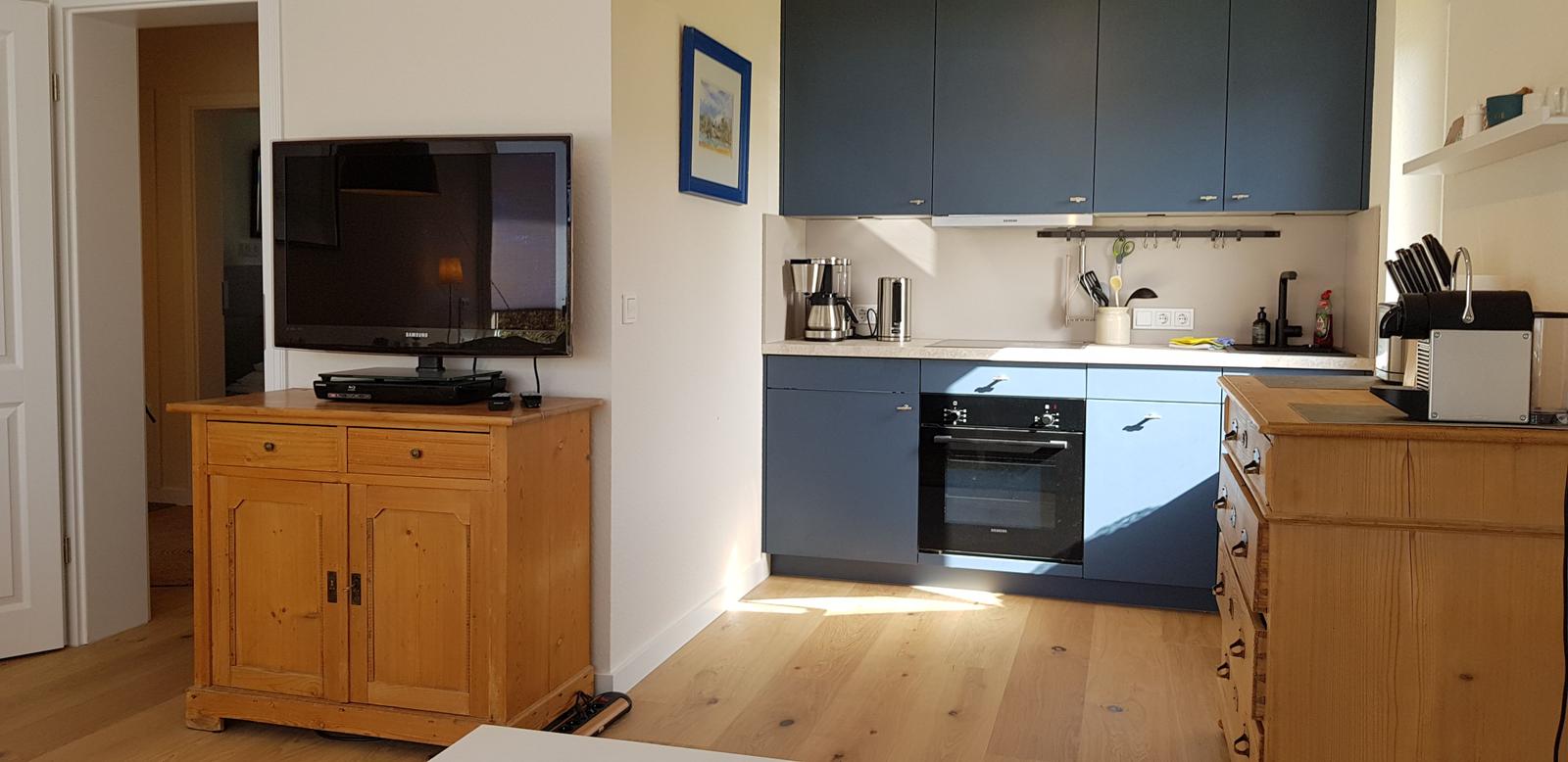 Küche mit blauen Schränken und Holzmöbeln. Fernseher auf einem Schrank.