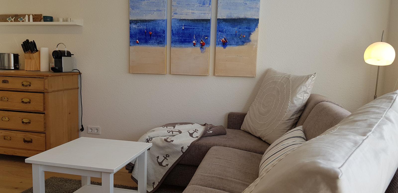 Wohnzimmer mit Sofa, Tisch und Wandbildern