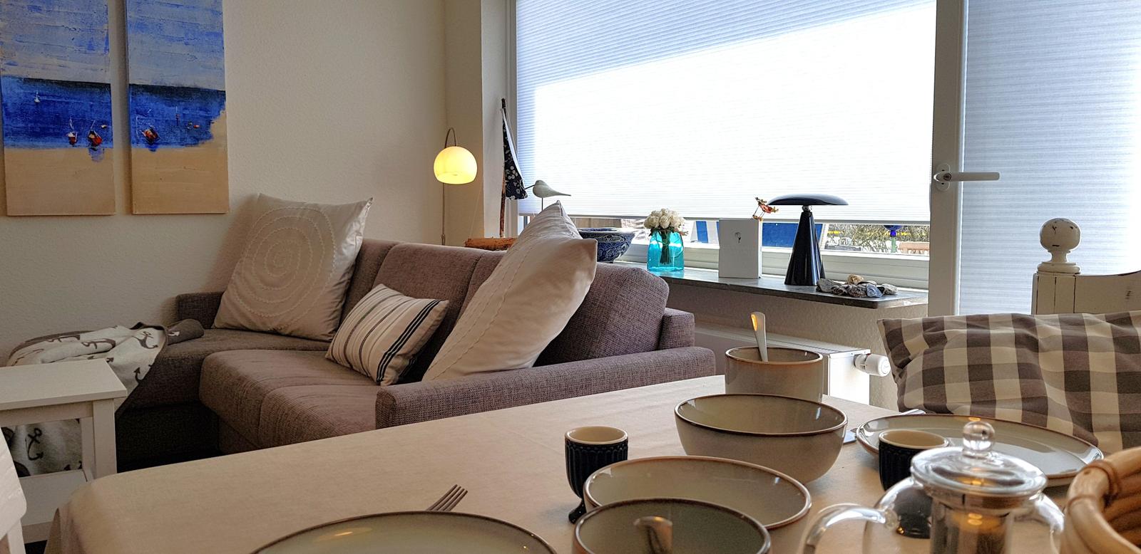 Wohn- und Essbereich mit Sofa, Tisch und Fensterblick.