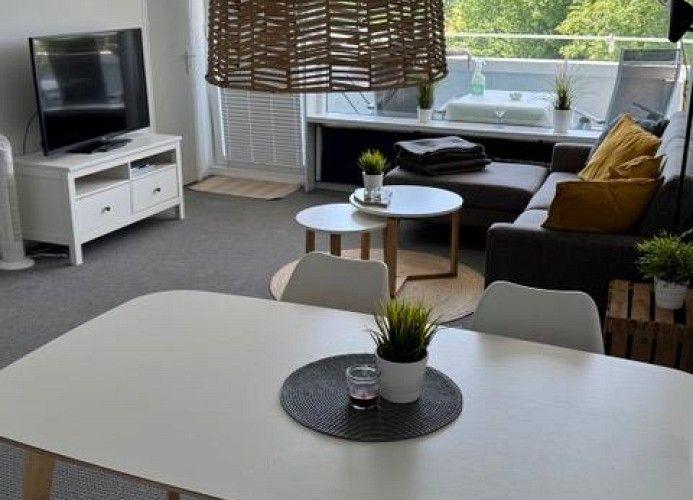 Wohnzimmer mit Essbereich, Sofa, TV und Balkon.