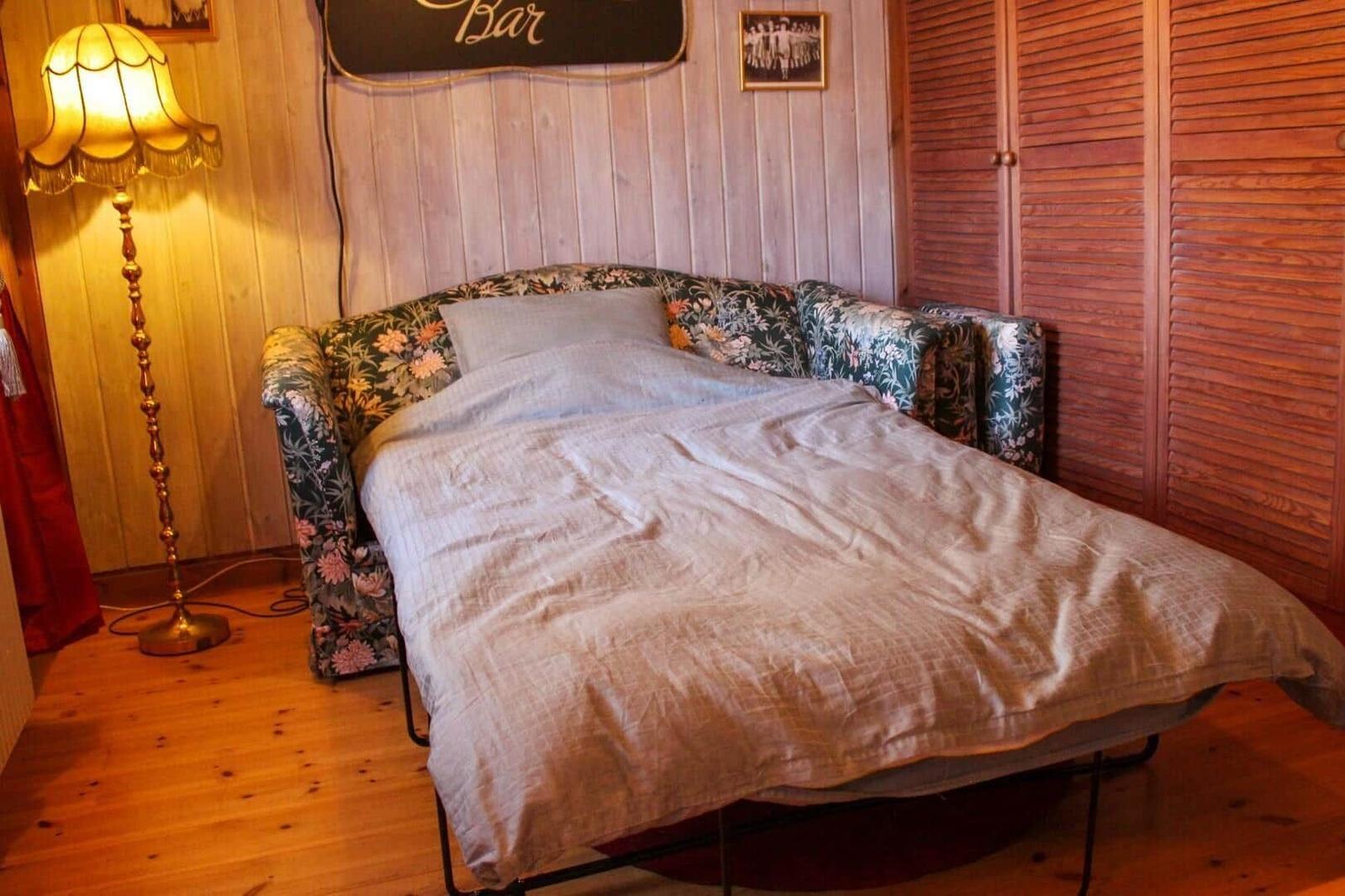 Schlafzimmer mit Bett, Lampe und Holzwand.