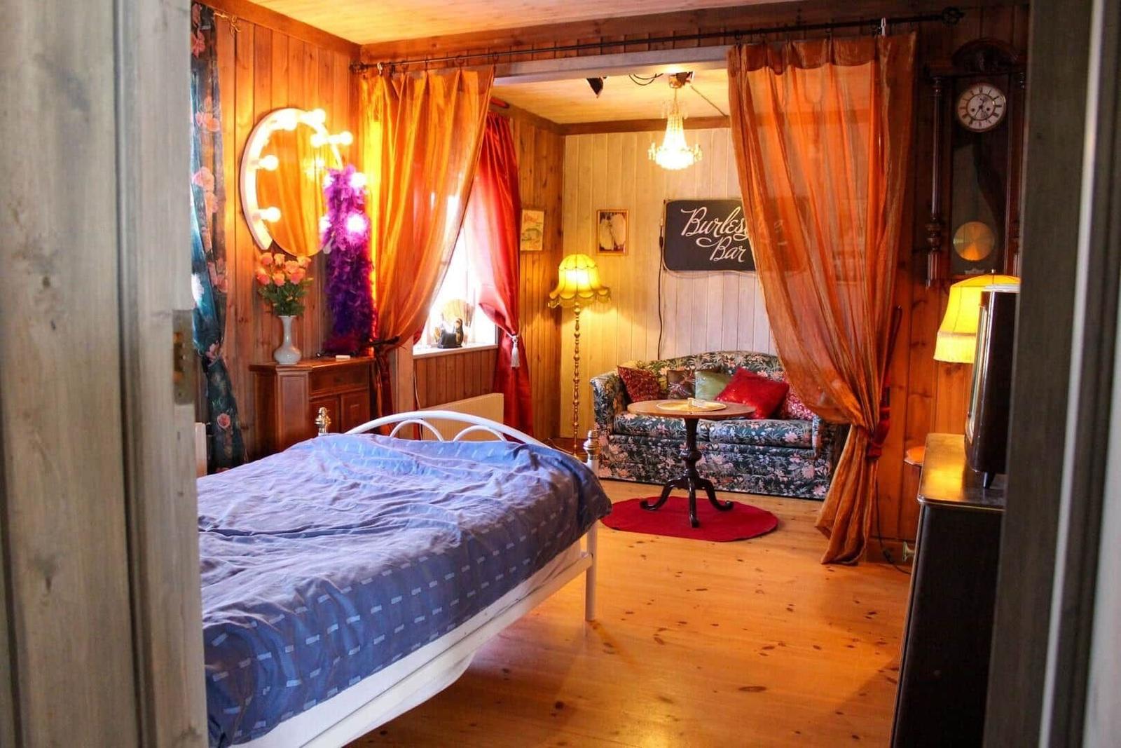 Schlafzimmer mit Bett, Spiegel und Sofa im Hintergrund.