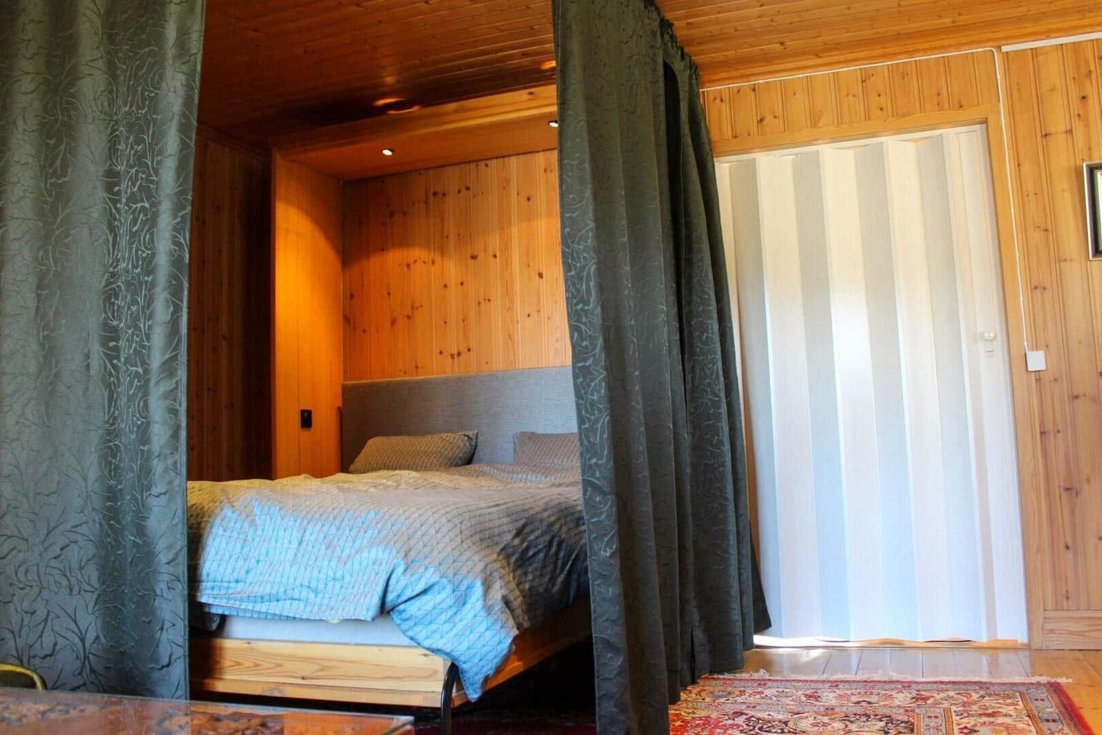 Schlafzimmer mit Bett, Vorhängen und Holzwand