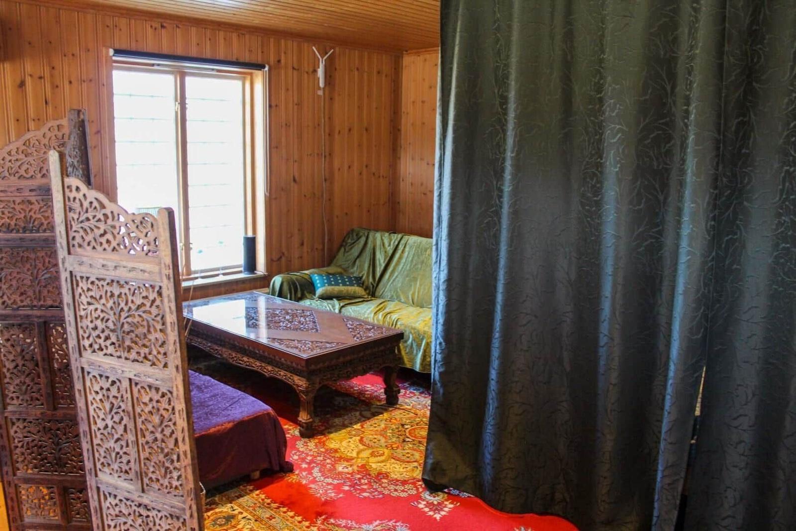 Ein Raum mit Holzwand, Sofa, Tisch und Vorhang.