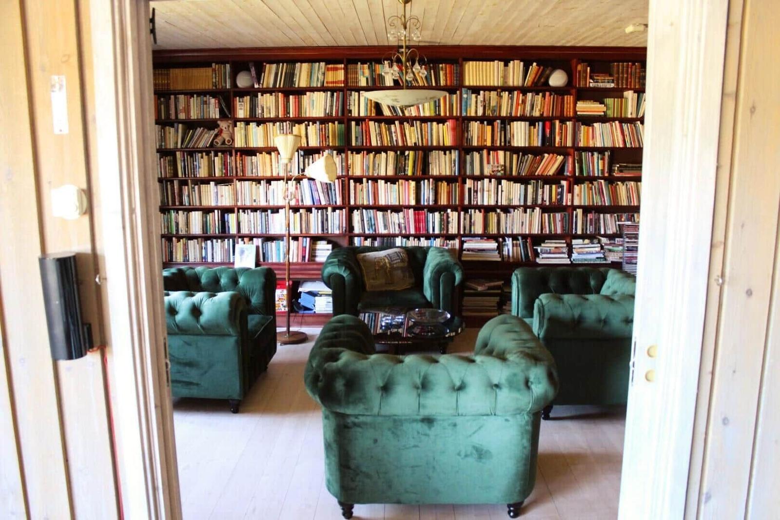 Ein Raum mit grünen Sesseln und einer Bücherwand.