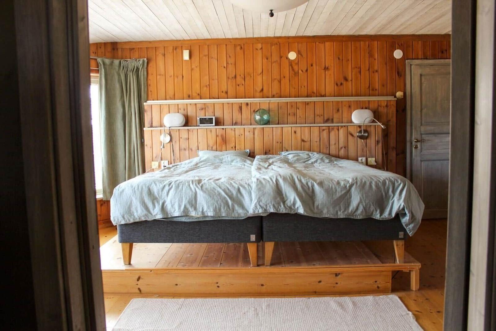Schlafzimmer mit Holzwand, Bett und Fenster