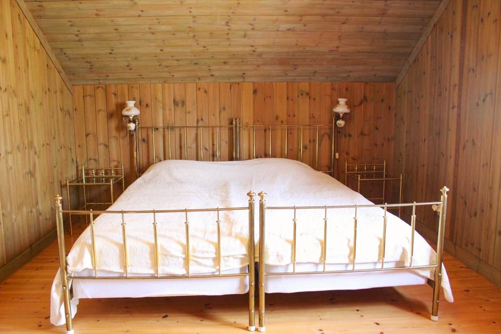 Schlafzimmer mit Holzwand und goldfarbenem Bettgestell.