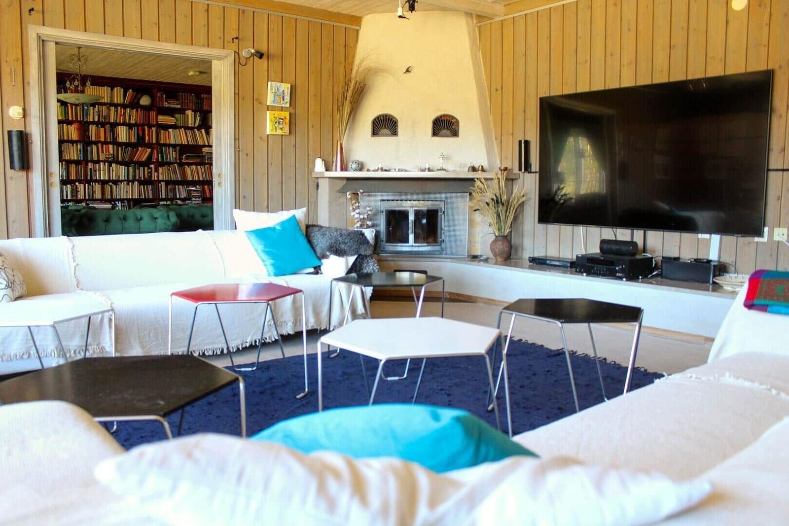 Wohnzimmer mit Sofa, Fernseher und Kamin. Bücherregal im Hintergrund.