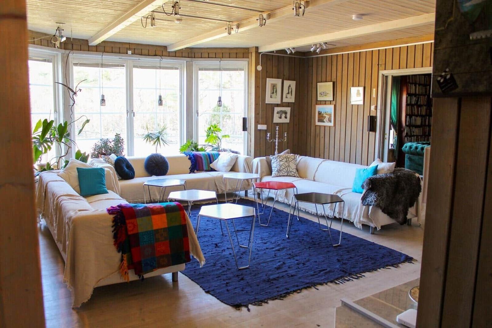 Wohnzimmer mit Sofa, Teppich und Fenstern. Wandgestaltung und Möbel sind sichtbar.