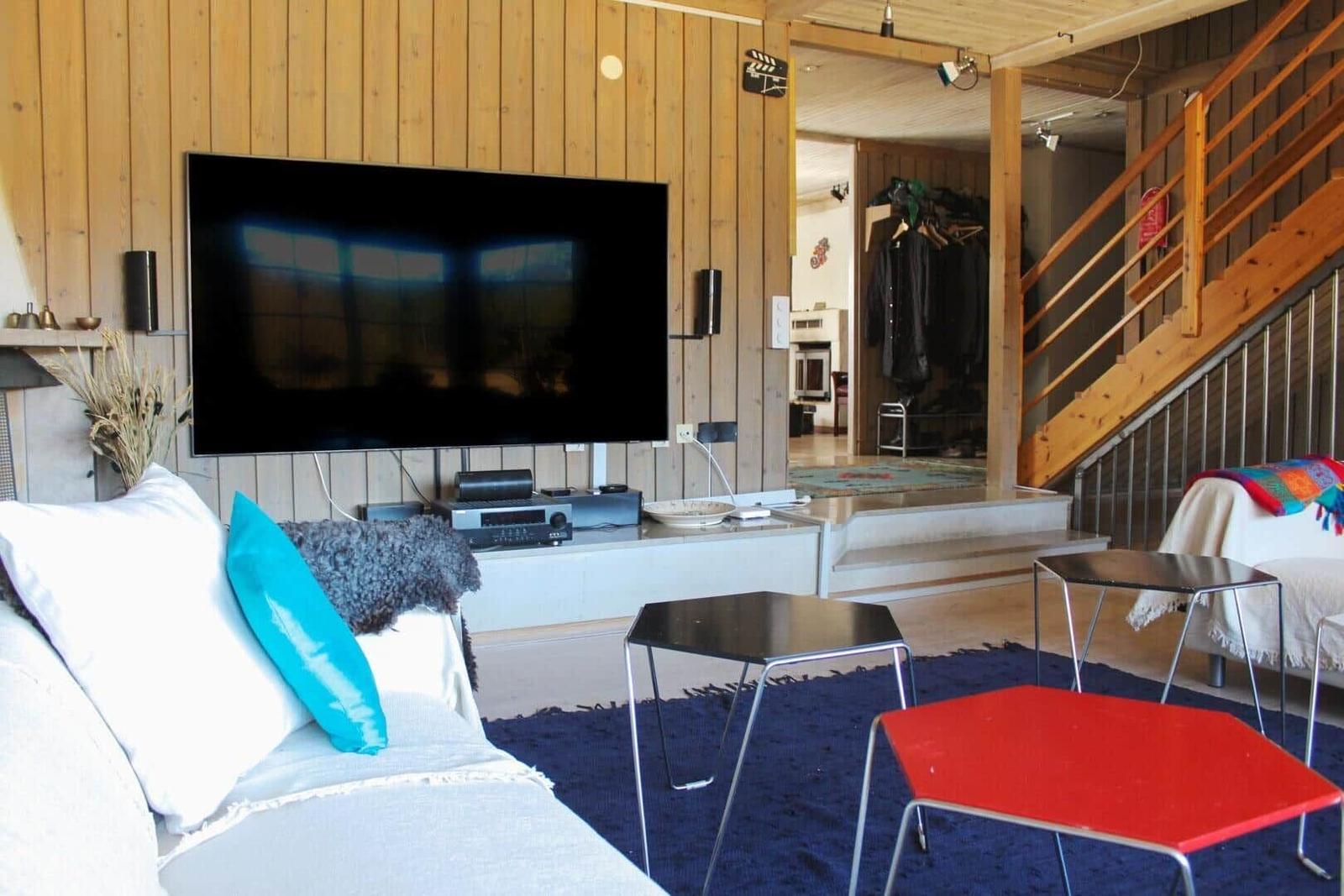 Wohnzimmer mit Sofa, TV, Tischen und Holzwand