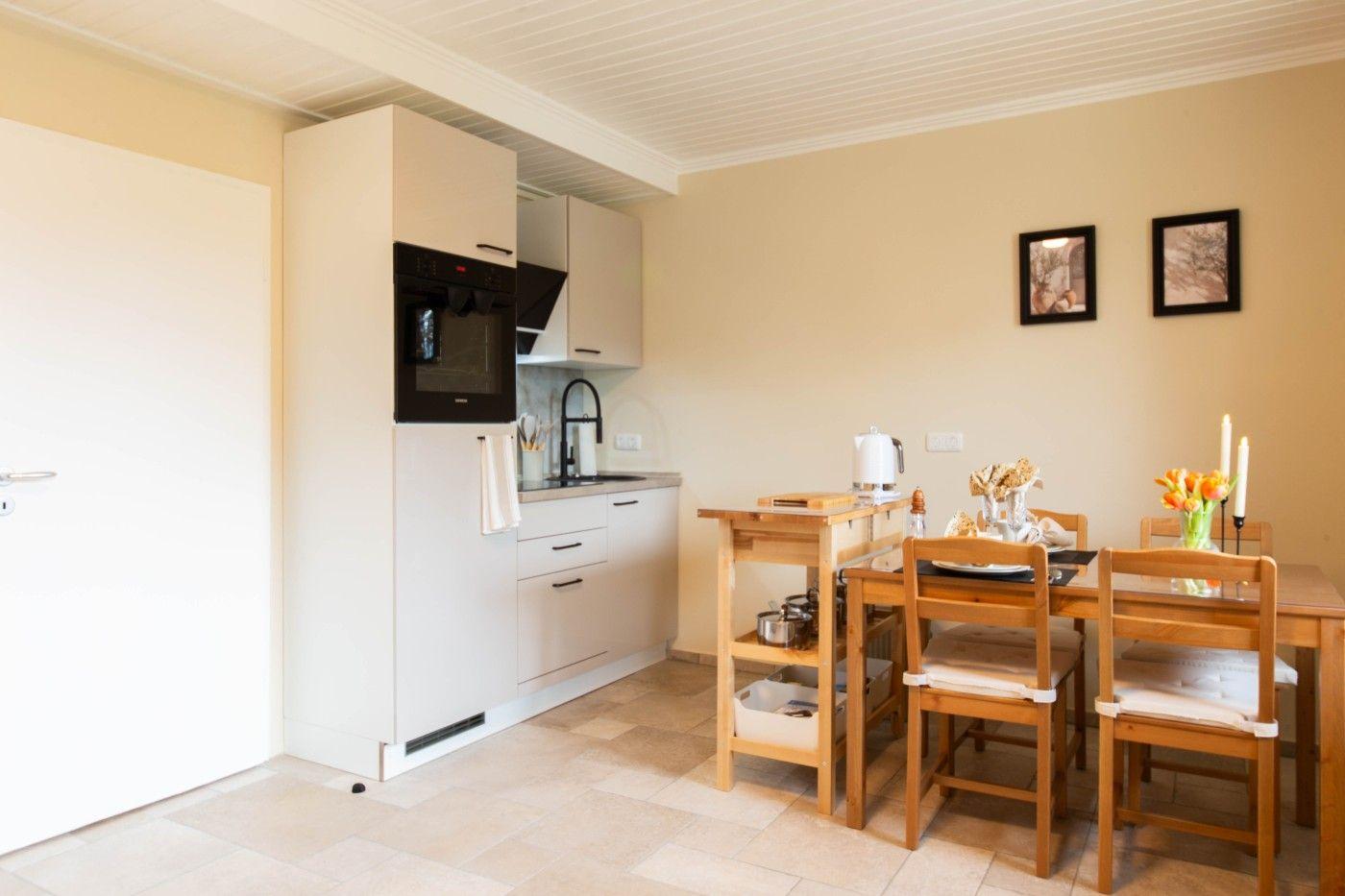 Küche mit Essbereich, Holztisch, Stühle und Küchenschränke.