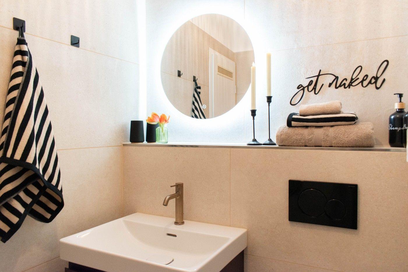 Badezimmer mit Waschbecken, runden Spiegel und Handtuchhalter.