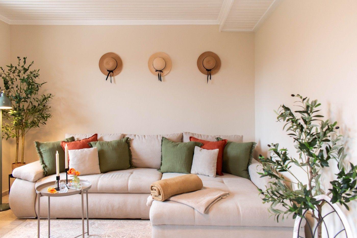 Ein Wohnzimmer mit Sofa, Kissen und Pflanzen an den Wänden.