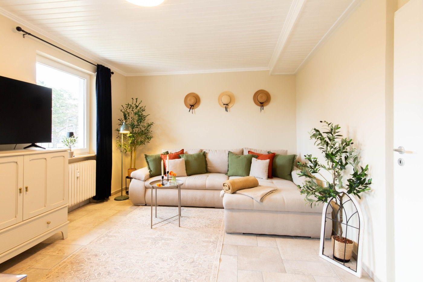 Wohnzimmer mit Sofa, Fernseher und Pflanzen.