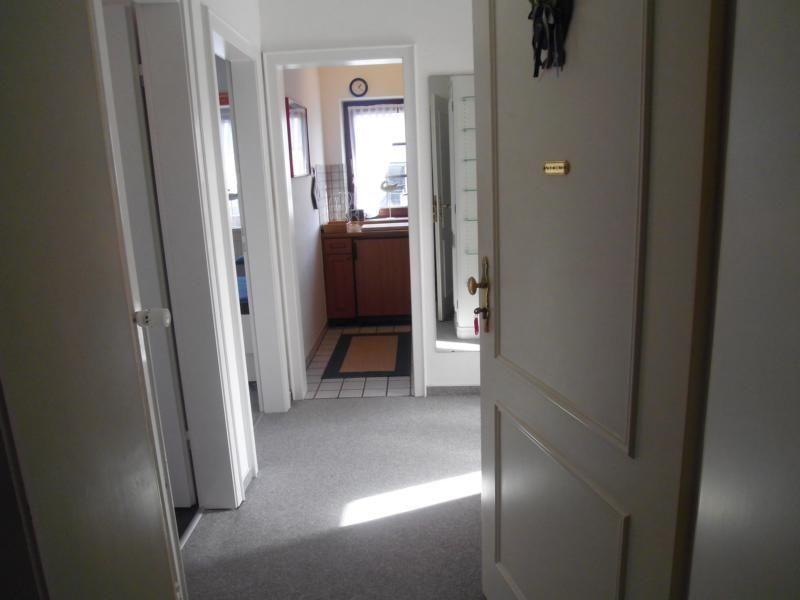 Flur mit Tür und Blick in Küche mit Holzschrank und Fenster