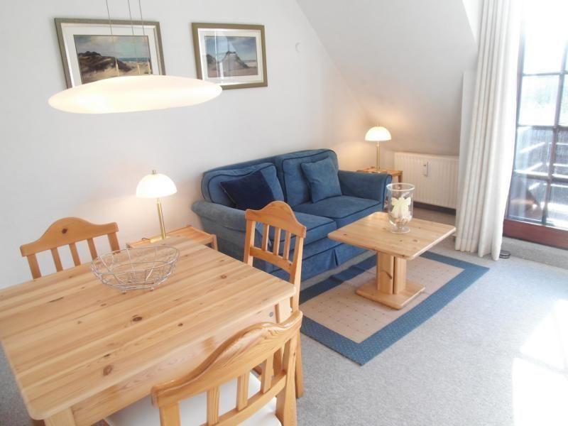 Wohn- und Essbereich mit Holztisch, Sofa und Fenster.