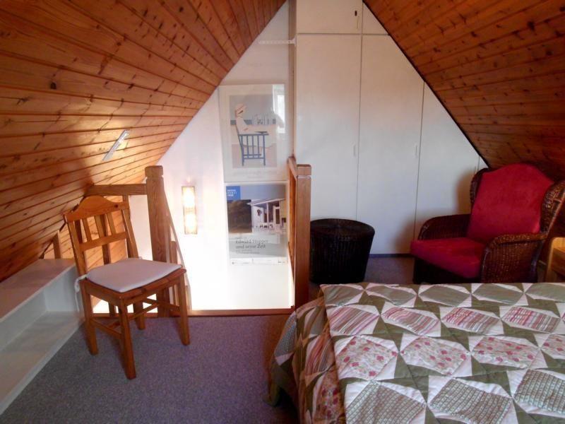 Schlafzimmer mit Dachschrägen, Bett, Stuhl und Sessel.