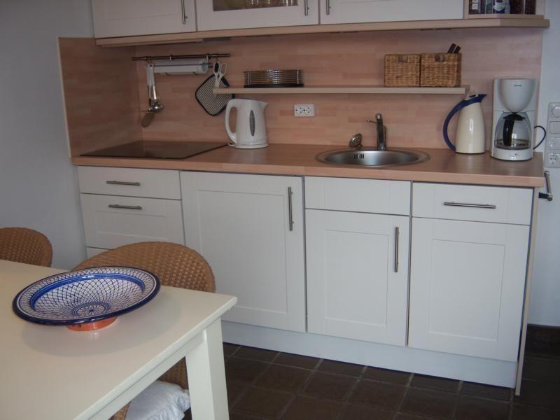 Küche mit Arbeitsplatte, Spüle, Kaffeemaschine und Tisch mit Schale.