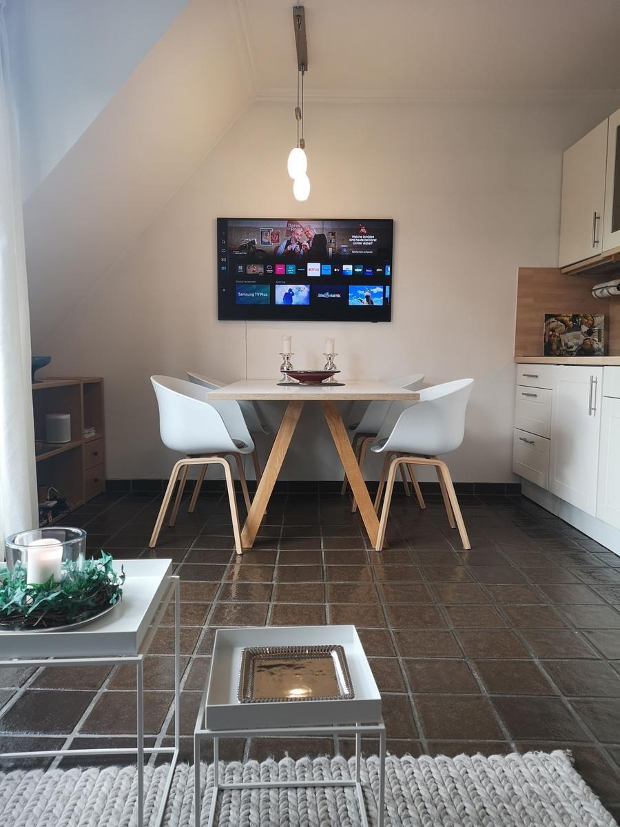 Essbereich mit Tisch, Stühlen und Fernseher an der Wand.