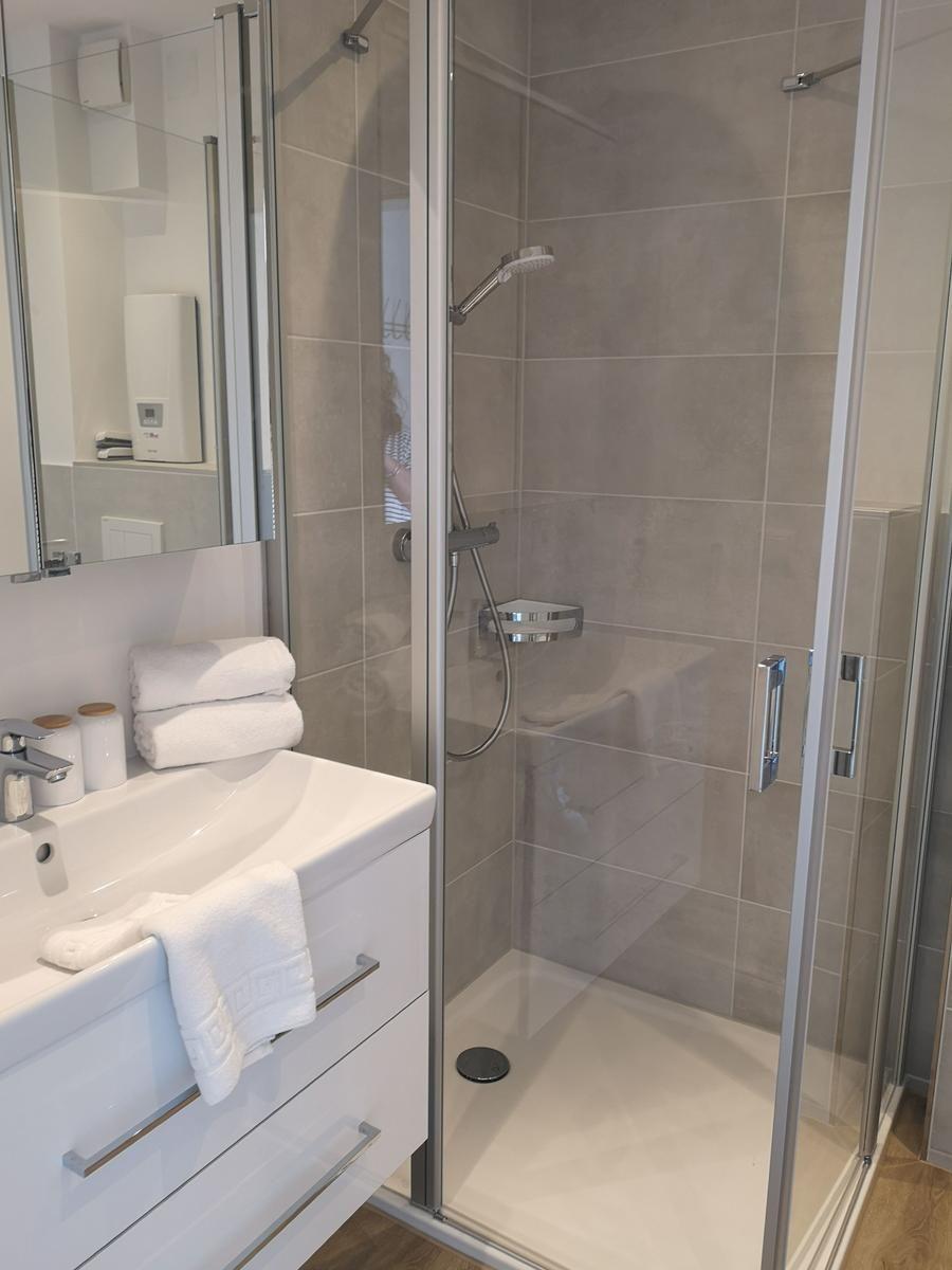 Badezimmer mit Dusche, Waschbecken und Spiegel