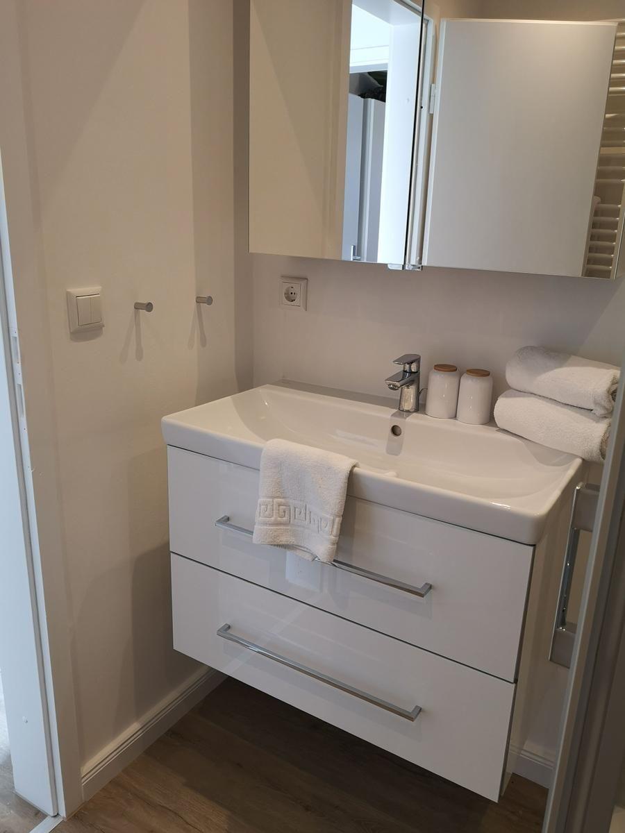 Weiße Waschbeckenunterschrank mit Spiegel und Handtüchern