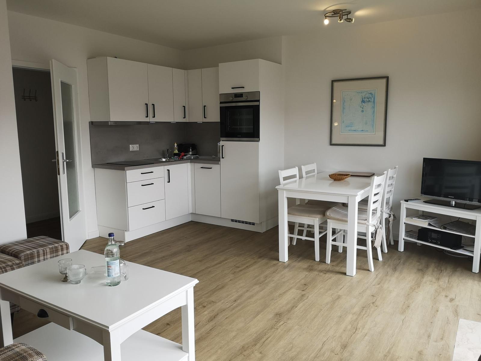 Küche mit Essbereich und Wohnbereich mit Fernseher und Tisch.