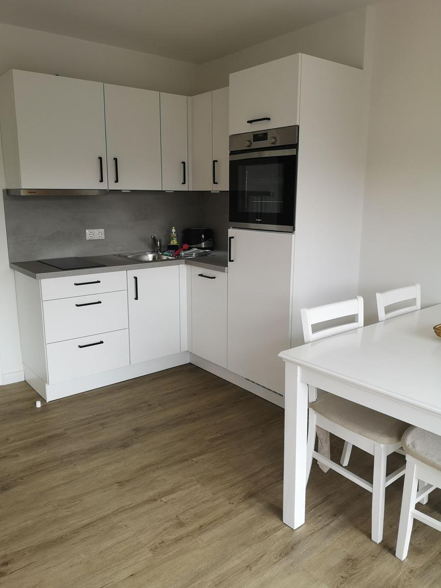 Küche mit weißer Einbauküche, Edelstahlherd und Esstisch mit Stühlen.