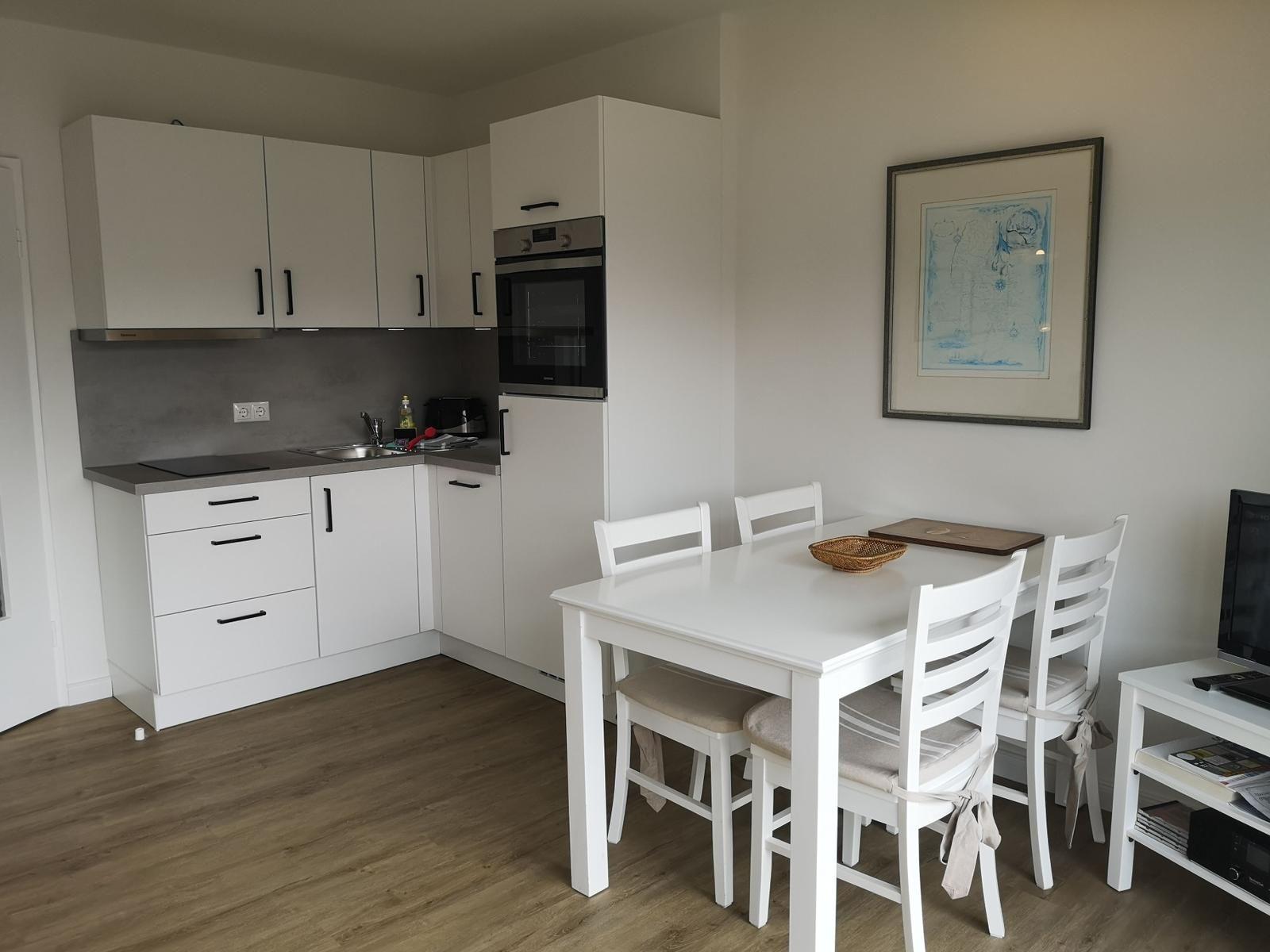 Küche mit Essbereich, weiße Möbel und Holzboden