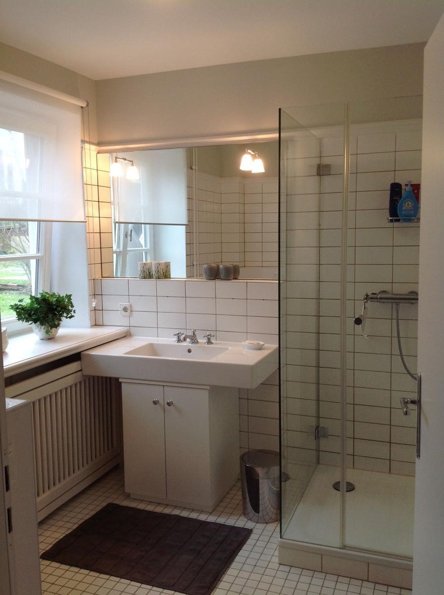 Badezimmer mit Dusche, Waschbecken und Fenster.