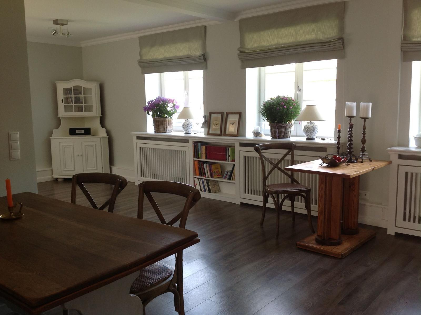 Eingangsbereich mit Tisch, Stühlen und Bücherregal unter Fenstern.