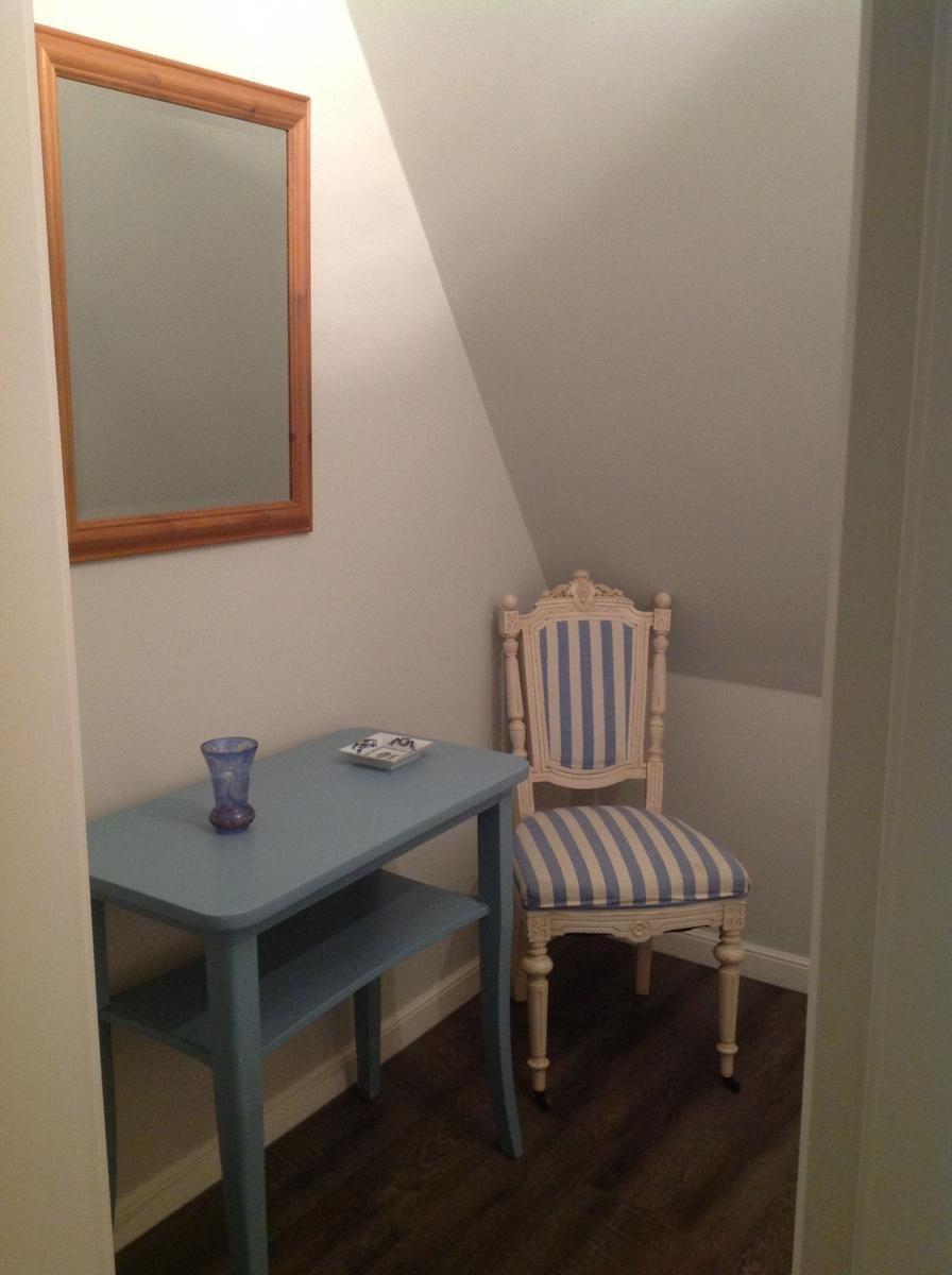 Ein kleiner Schreibtisch mit Stuhl und Spiegel an der Wand.