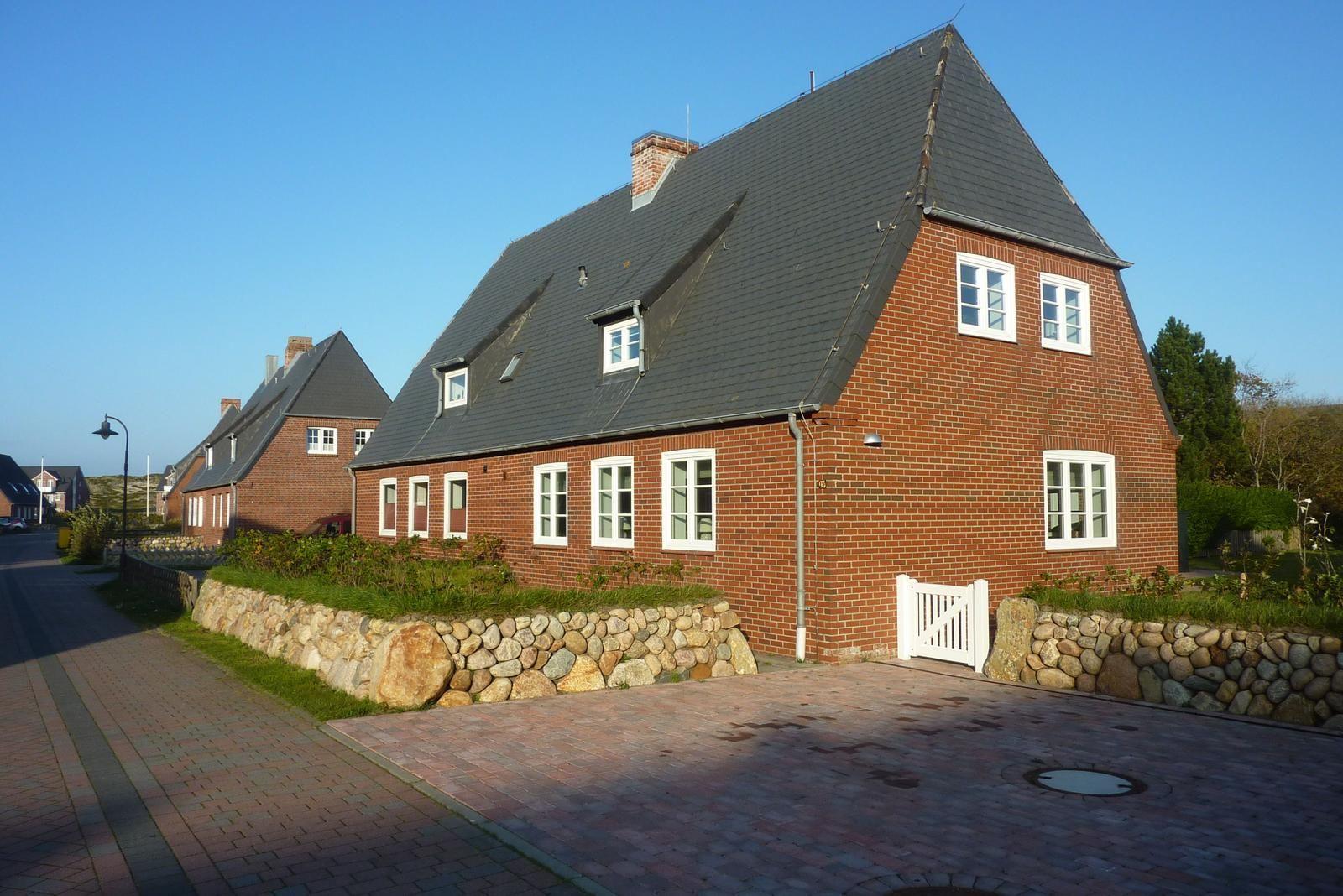 Rotes Backsteingebäude mit Dachfenstern und Steinmauer
