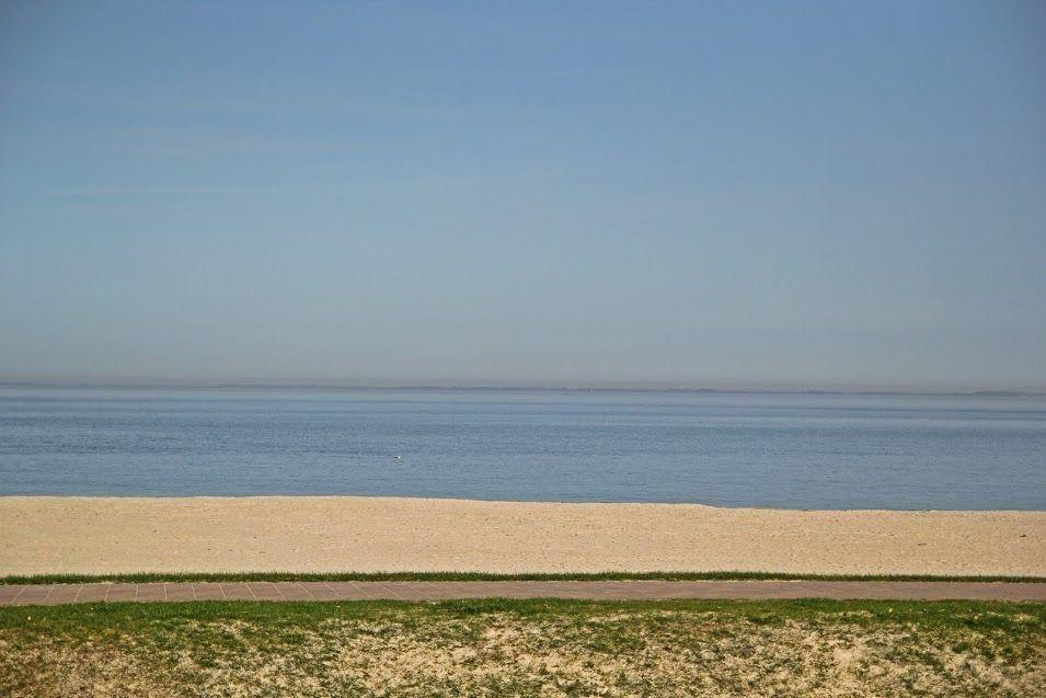 Strand mit Sandstrand und ruhigem Meer unter klarem Himmel.
