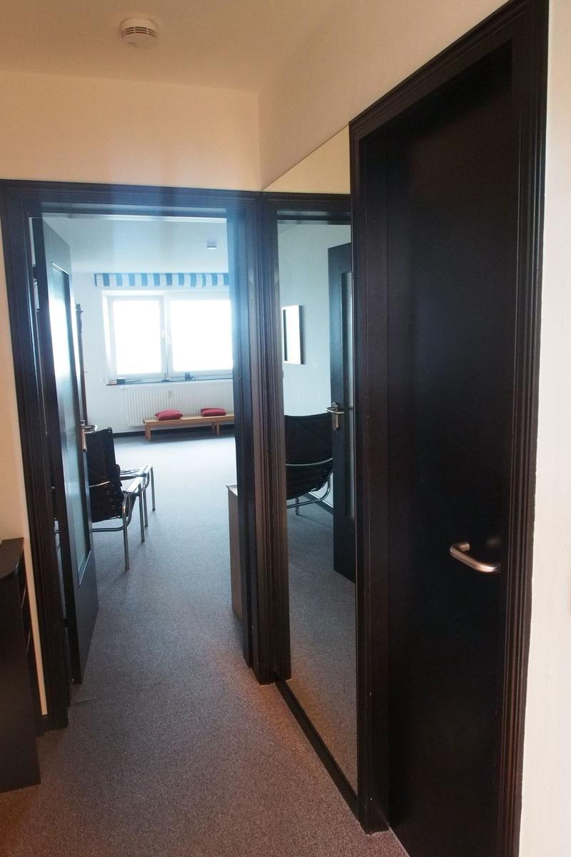 Flur mit Blick in Wohn- und Schlafzimmer mit Fenster und Sitzbank.