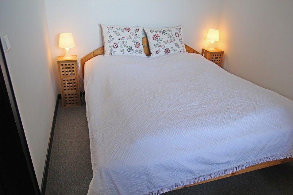 Schlafzimmer mit Bett, zwei Nachttischen und Lampen.