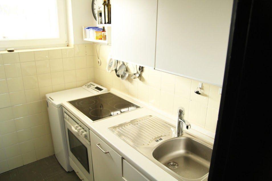 Küche mit Herd, Spüle und weißen Schränken