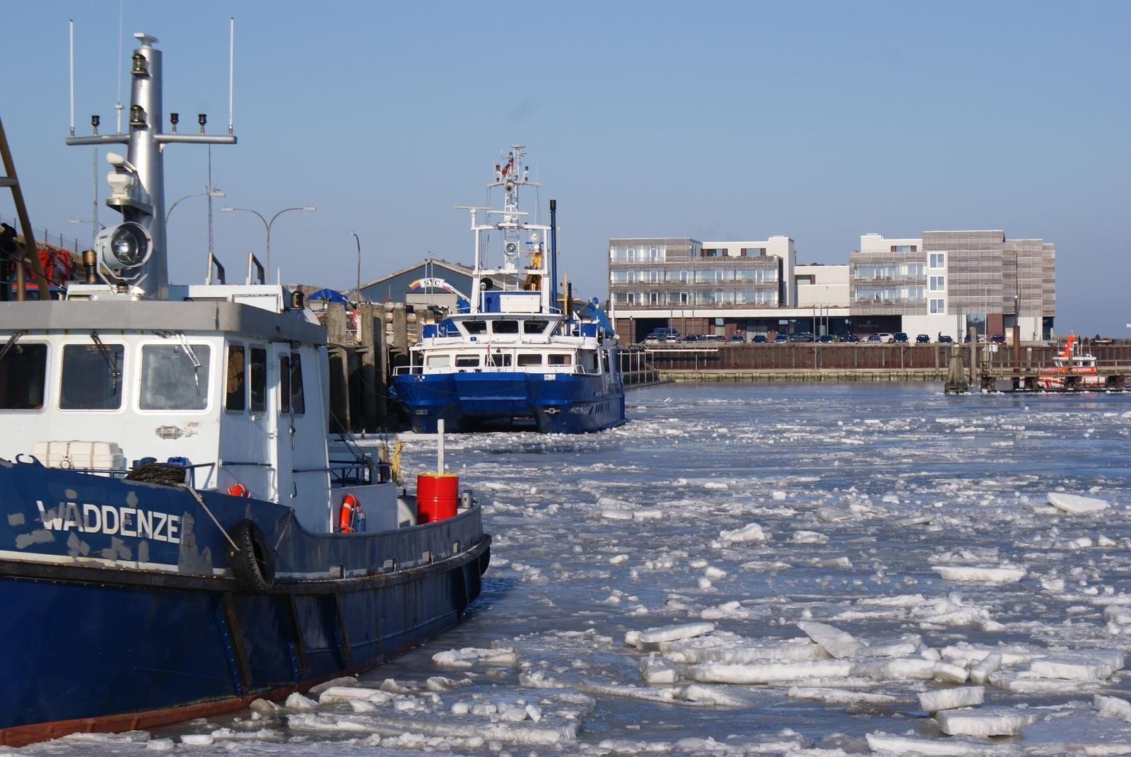 Hafen mit Eis und Schiffen. Blick auf moderne Gebäude im Hintergrund.