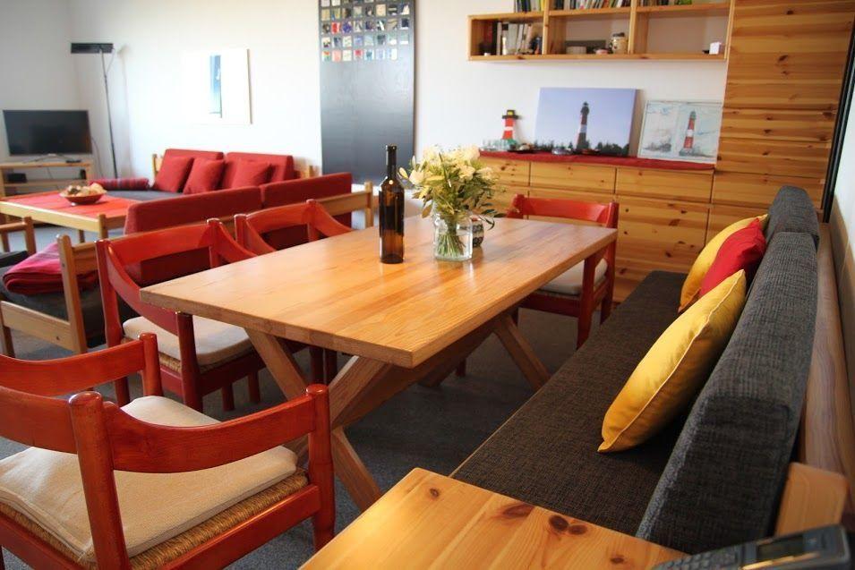 Essbereich mit Holztisch, roten Stühlen und Sofa mit Kissen.