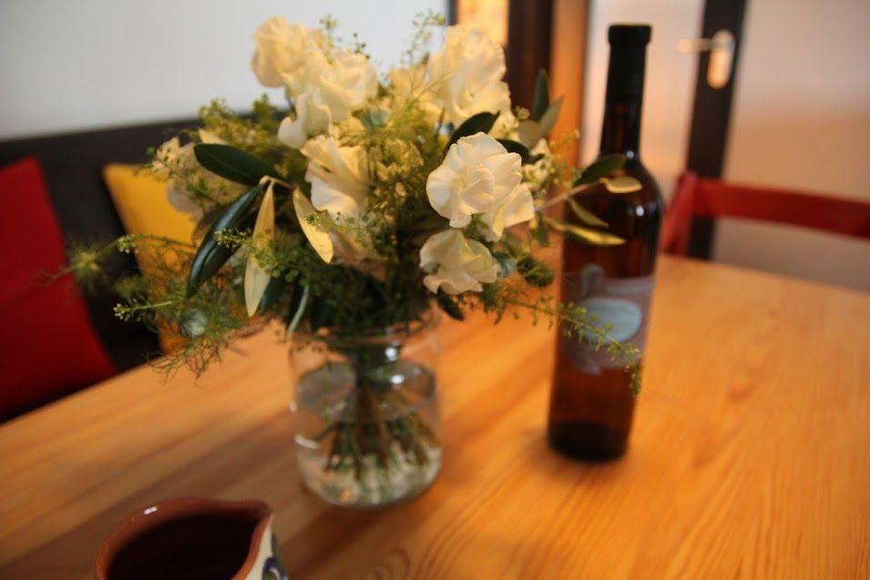 Auf dem Tisch steht eine Blumenvase und eine Weinflasche.