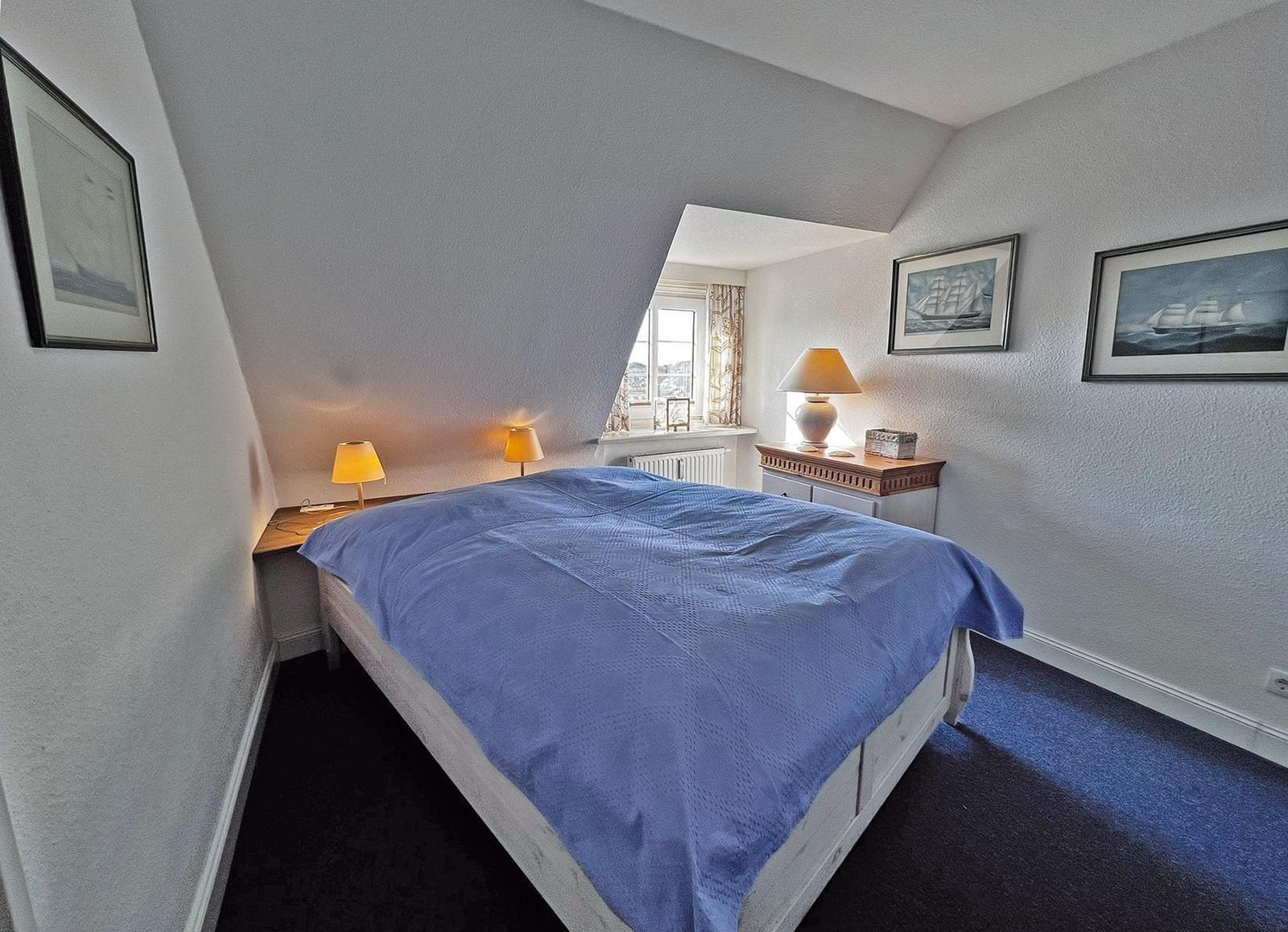 Schlafzimmer mit Bett, Nachttischen und Fenster