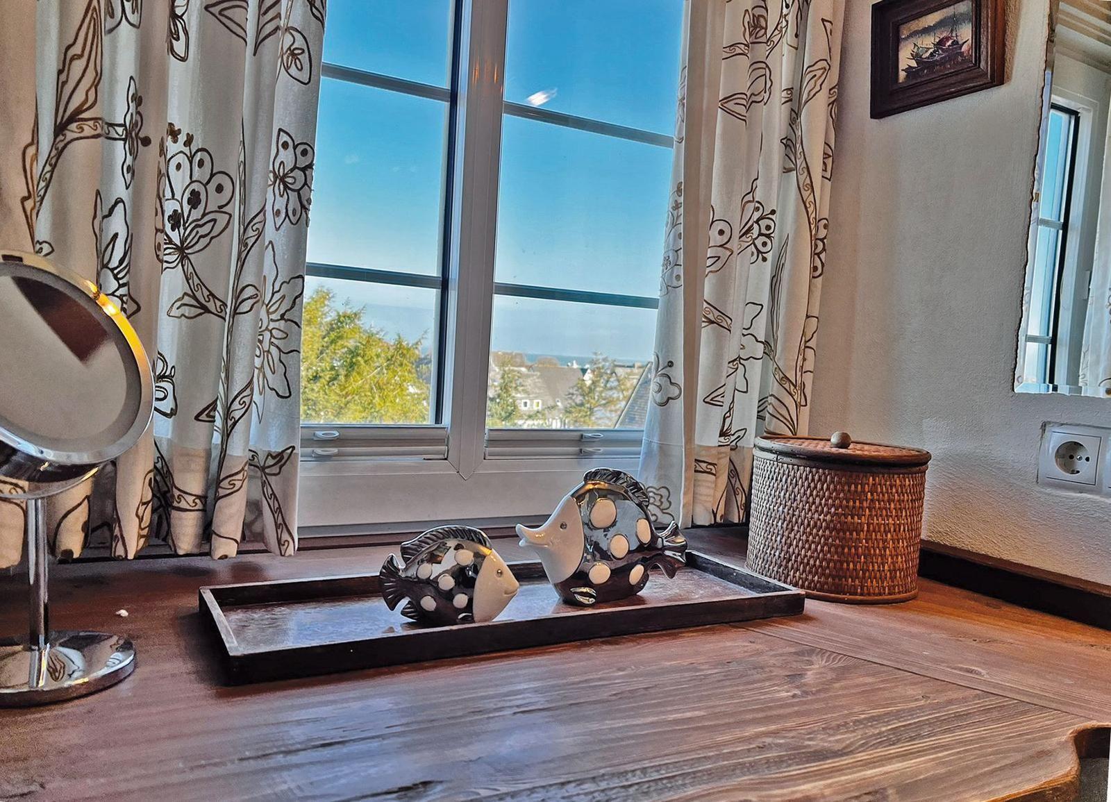 Holztisch mit Fischdekoration und Blick aus dem Fenster