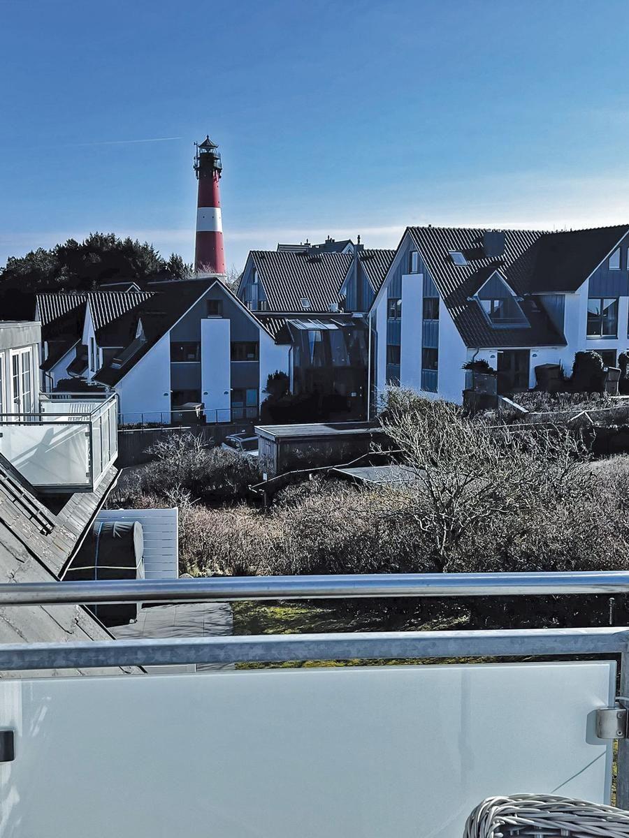 Blick von Balkon auf Leuchtturm und moderne Häuser.