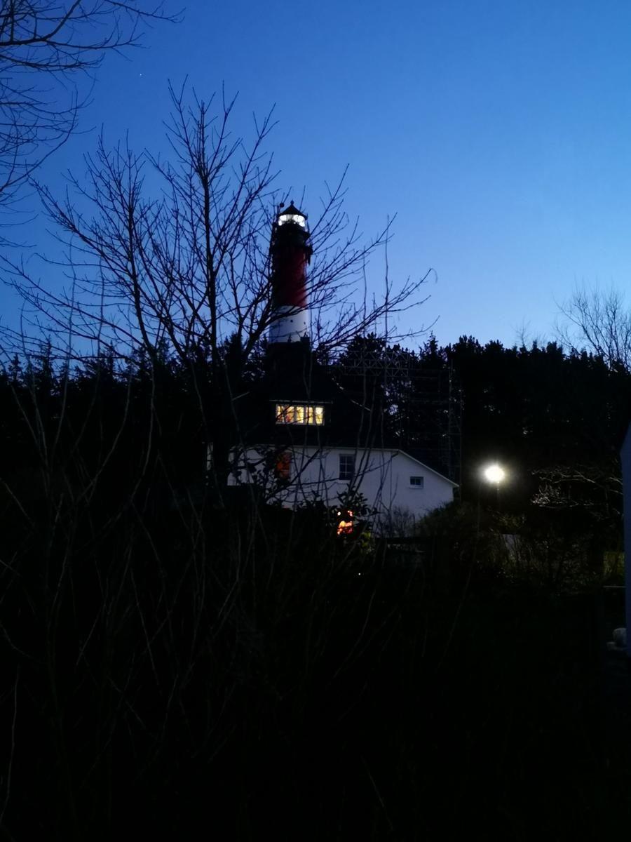 Roter Leuchtturm mit beleuchteter Laterne bei Dämmerung
