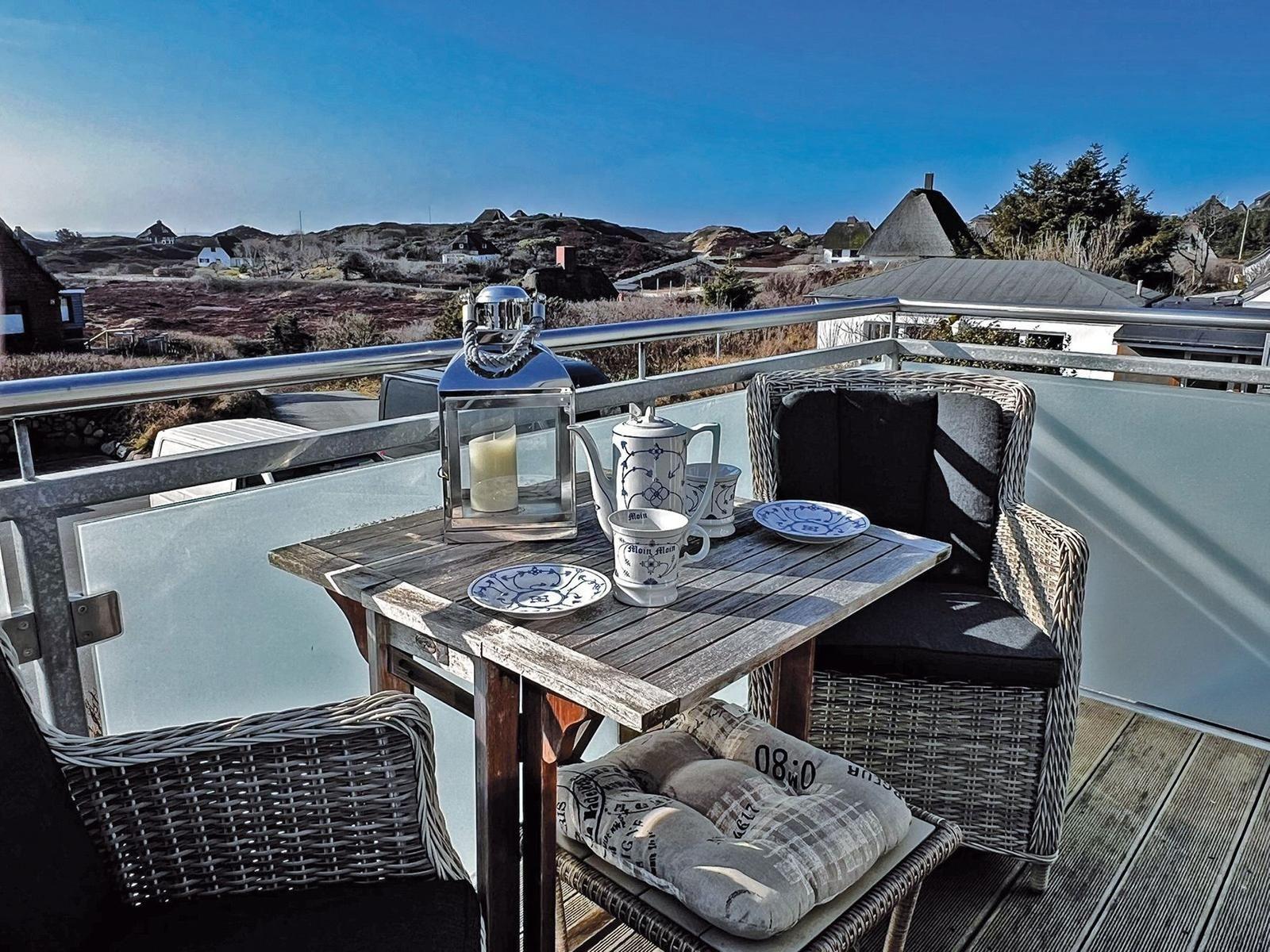 Terrasse mit Tisch, Stühlen und Blick auf die Landschaft.