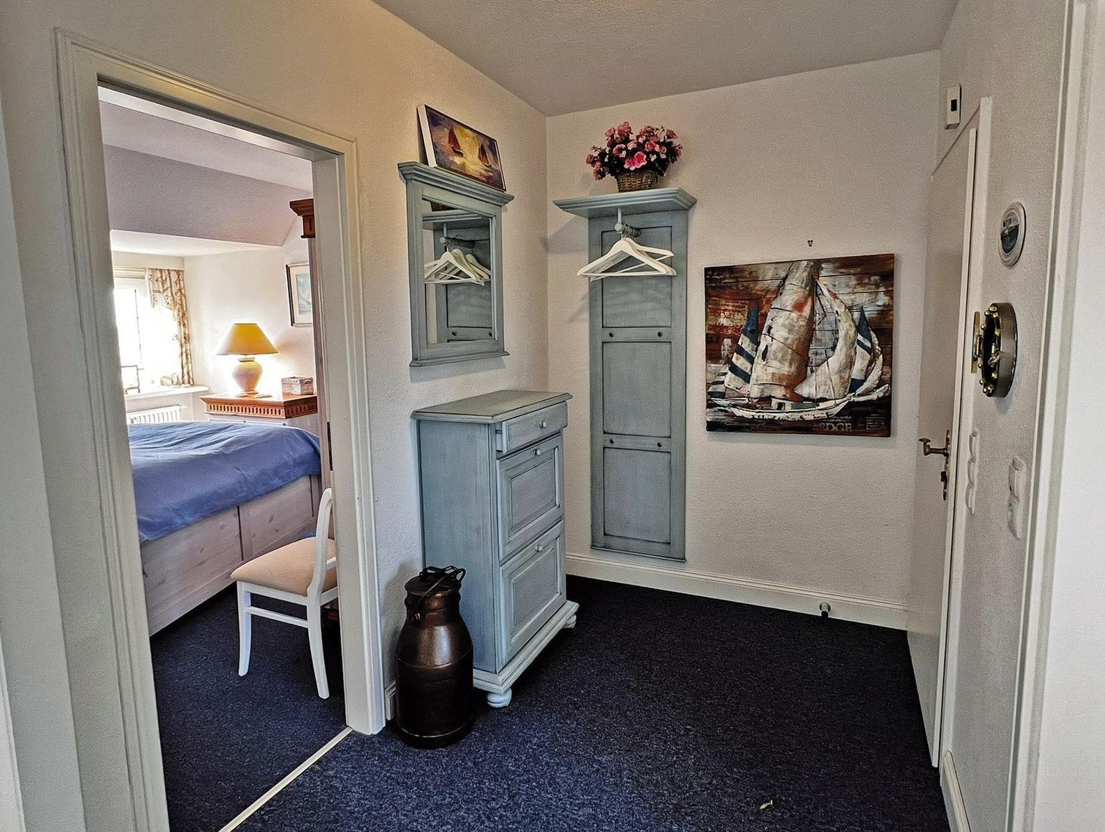 Flur mit Kleiderschrank, Wandbild und Blick in Schlafzimmer mit Bett.